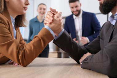 İş adamları, ofisteki tahta masada bilek güreşi yapıyor, seçici bir odaklanma.