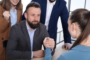 İş adamları, ofisteki tahta masada bilek güreşi yapıyorlar.