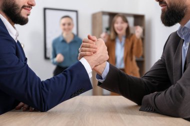 İş adamları, ofisteki tahta masada bilek güreşi yapıyor. Seçici bir odak noktası.