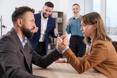 İş adamları, ofisteki tahta masada bilek güreşi yapıyor, seçici bir odaklanma.