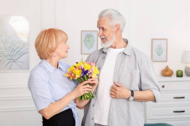 Evde bir buket çiçekleri olan sevimli yaşlı çift.