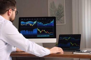 Borsa. Kapalı alandaki bilgisayarda finansal piyasayı analiz eden adam.