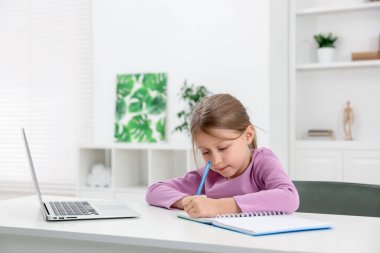 Küçük kız ev ödevlerini içeride yapıyor.