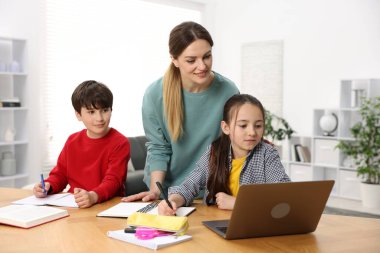 Anne, çocuklarına ev ödevlerinde yardım ediyor.