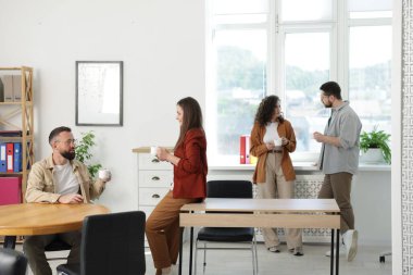 Ofiste kahve molası sırasında iş arkadaşları sohbet ediyor.