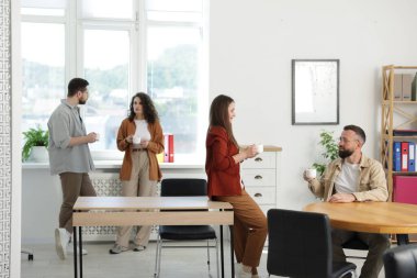 Ofiste kahve molası sırasında iş arkadaşları sohbet ediyor.