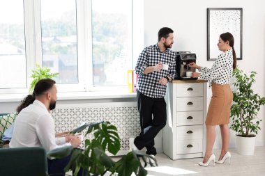 Ofiste kahve molası sırasında iş arkadaşları sohbet ediyor.