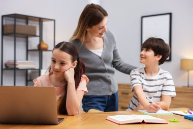 Anne, çocuklarına ev ödevlerinde yardım ediyor.