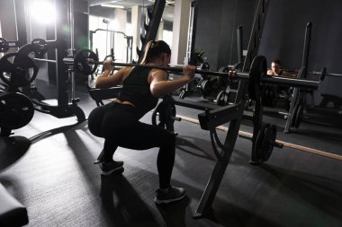 Spor salonunda halterle antreman yapan atletik bir kadın.