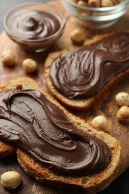 Çikolata sürülmüş ekmek dilimleri ve ahşap tahtada fındıklar, yakın plan.