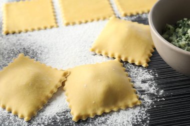 Pişmemiş ravioli, ahşap masaya doldurulmuş un, yakın plan.