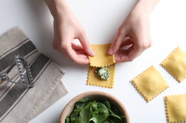 Beyaz masada peynirli ve ıspanaklı ravioli yapan kadın.