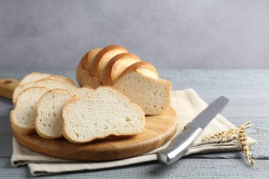 Gri ahşap masada dilimlenmiş ekmek ve bıçak