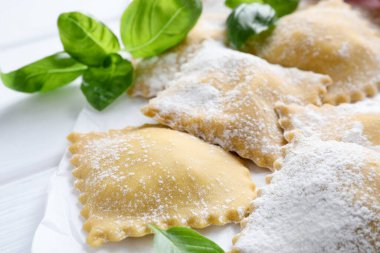 Beyaz masada pişmemiş mantı ve fesleğen, yakın plan.