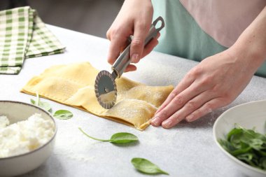 Işık masasında ravioli kesen kadın, yakın plan.