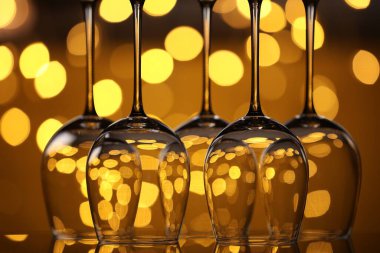 Bulanık ışıklara karşı cam ayna yüzeyinde birçok temiz bardak, yakın plan. Bokeh etkisi