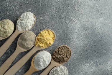 Gri masadaki kaşıklarda farklı türde un, düz. Metin için boşluk