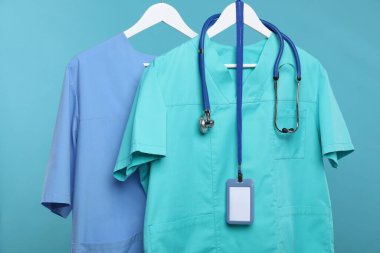 Steteskop ve rozetli sağlık çalışanları üniformaları mavi arka planda.