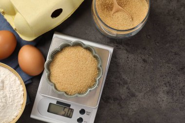 Mutfak terazisi, bir kase un ve gri masa üzerindeki diğer ürünler, düz yatak. Metin için boşluk