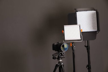 Profesyonel ışıklandırma ekipmanı ve gri arka planda kamera. Metin için boşluk