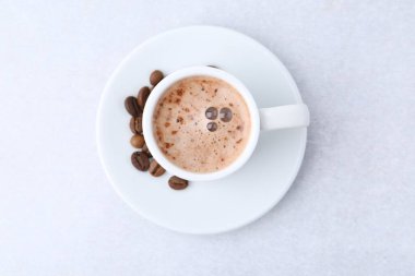 Aromatik kahve fincanda, fasulye ve çay tabağı ışık masasında, üst manzara.