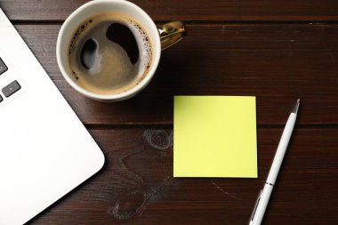 Yapışkan not, kalem, kahve ve dizüstü bilgisayar ahşap masada, düz yatıyordu.