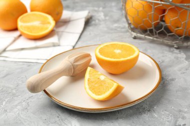 Tahta sıkacağı ve taze portakallar gri masada, yakın plan.