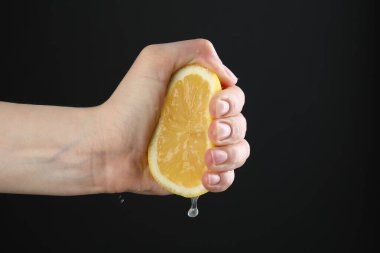 Siyah arka planda limon sıkan kadın, yakın plan.