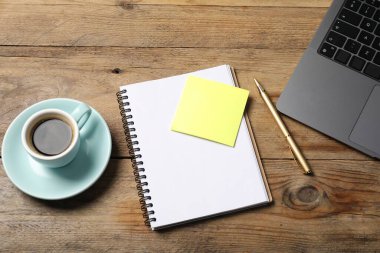 Üzerinde kalem, yapışkan not, dizüstü bilgisayar ve kahve olan bir defter.