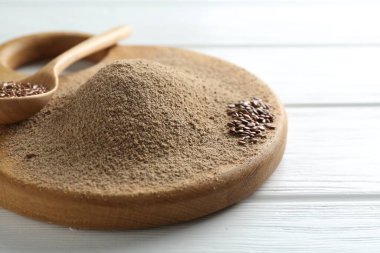 Keten tohumu unu ve kaşıkla beyaz ahşap masada tohumlar, yakın plan.