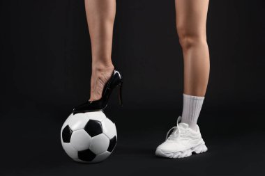 Arka planda futbol topu olan yüksek topuklu ayakkabılı ve spor ayakkabılı bir kadın.