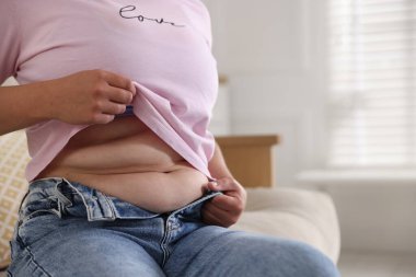 Evde göbeği aşırı yağlı bir kadın, yakın çekim ve mesaj için yer. Aşırı kilolu