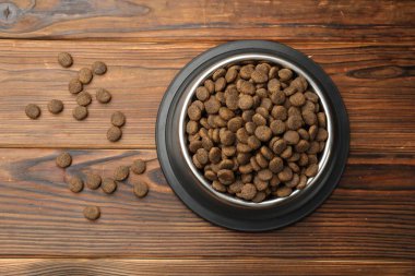 Tahta arka planda besleme kabında kurutulmuş hayvan mamaları, üst manzara.