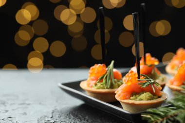 Lezzetli kanepeler ve siyah masa üzerindeki Noel dekoru bulanık ışıklı karanlık arka plan, yazı için yer. Bokeh etkisi