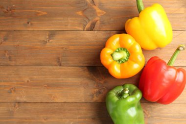 Ahşap masanın üzerinde olgun renkli dolmalık biberler, düz yatıyordu. Metin için boşluk