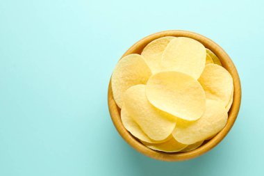 Açık mavi arka planda, kasede leziz patates cipsi, üst manzara. Metin için boşluk
