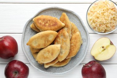 Lezzetli kızarmış pirizky (doldurulmuş turtalar) ve beyaz ahşap masa üzerinde elmalar, düz yatıyordu.