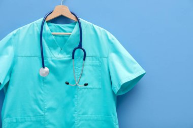 Mavi arka planda steteskop takılı sağlık çalışanı üniforması.