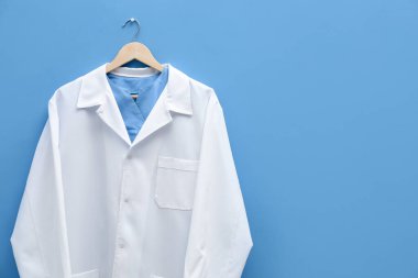 Doktorun ceketi mavi arka planda asılı. Metin için boşluk