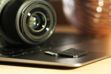 SD hafıza kartları, dizüstü bilgisayar ve fotoğraf makinesi masada, yakın plan.