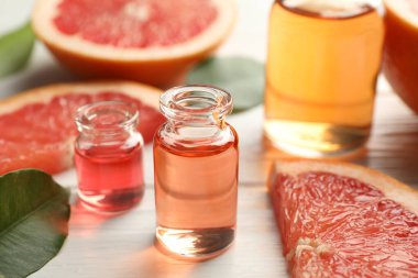 Aromatik esanslı parfüm şişelerini beyaz ahşap masada yapraklar ve dilimler halinde açın.