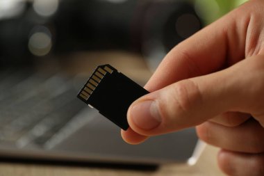 Bulanık arkaplanda SD hafıza kartı olan adam, yakın plan