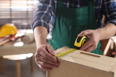 İçerideki bantla ahşap rafı ölçen adam.