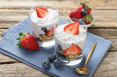 Chia tohumlu lezzetli tatlı, yoğurt, granola, çilek ve böğürtlen ahşap masada, yakın plan. Süper yemek.