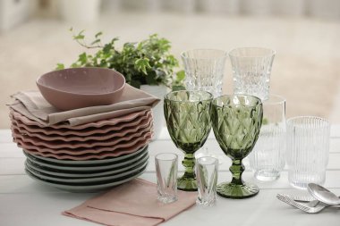 Temiz bardaklar, tabaklar, çatal bıçak takımı ve yeşil saksı.