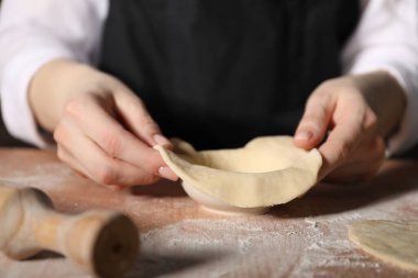 Khinkali yapıyorum. Mutfaktaki masada hamur şekillendiren kadın, yakın plan.