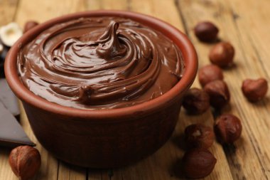 Lezzetli çikolatalı fındık ezmesi ve fındıklar ahşap masada, yakın plan.