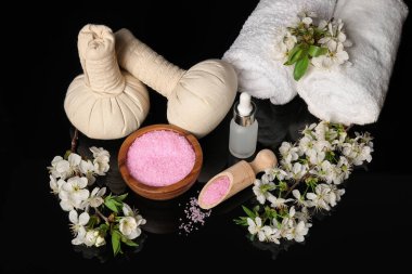 Siyah ayna yüzeyinde kozmetik ürünleri ve güzel çiçeklerle kaplıca kompozisyonu.