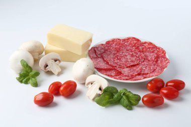 Pizza yapıyorum. Farklı malzemeler beyaza izole edilmiş.