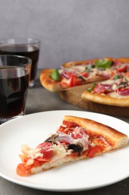 Gri masada servis edilen ince tütsülenmiş sosisli, lezzetli bir pizza.